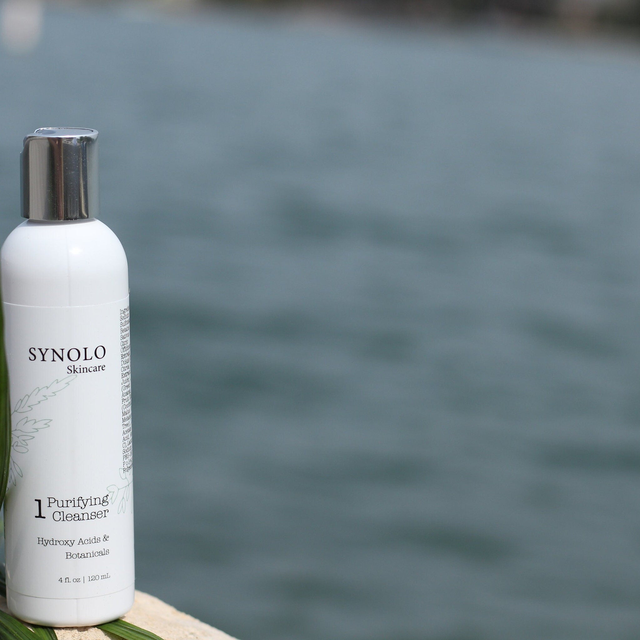Purifying cleanser bottle, white with silver cap, Synolo Skincare label on bottle