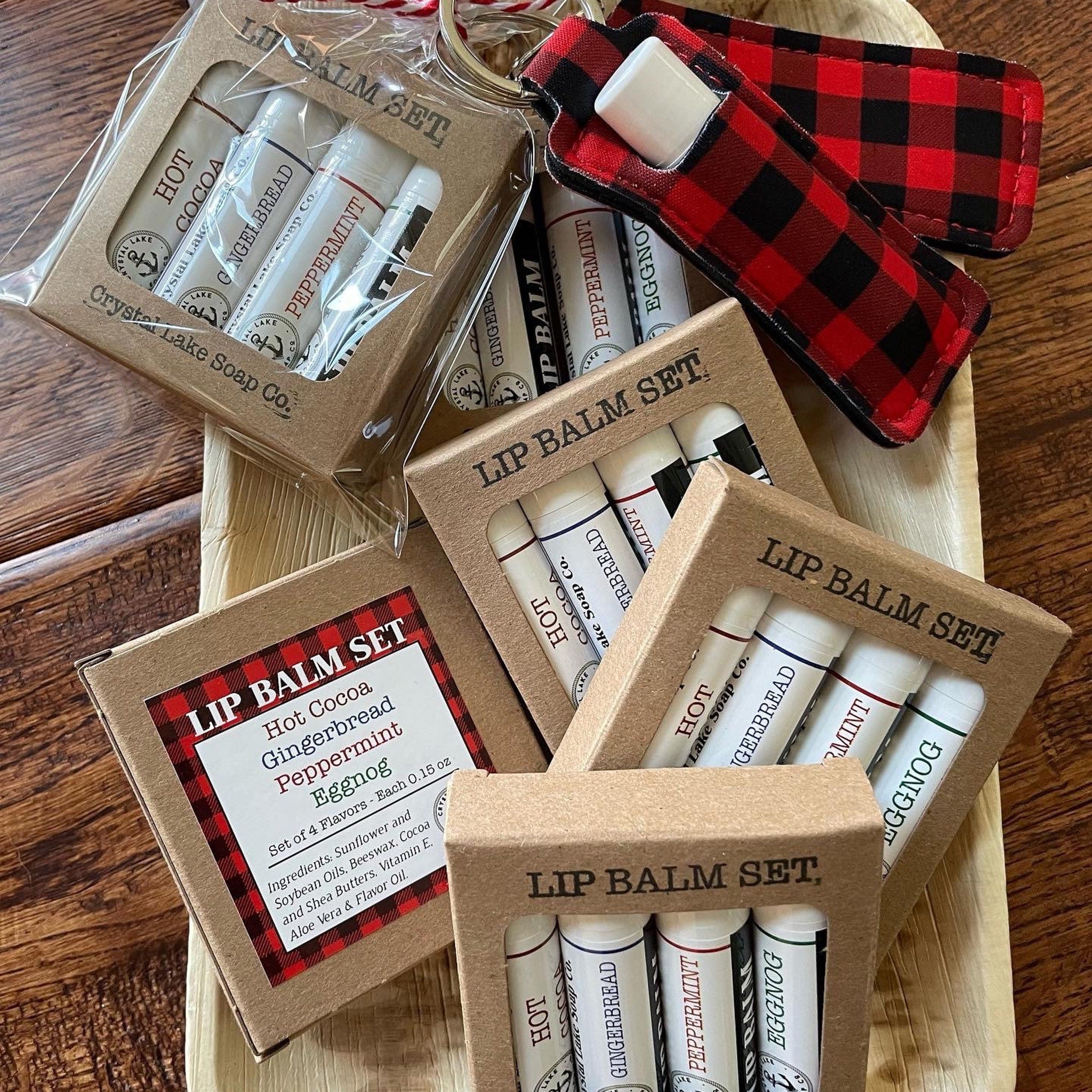 Lip balm sets in cardboard boxes with red and black plaid lip balm holder, for gift giving.