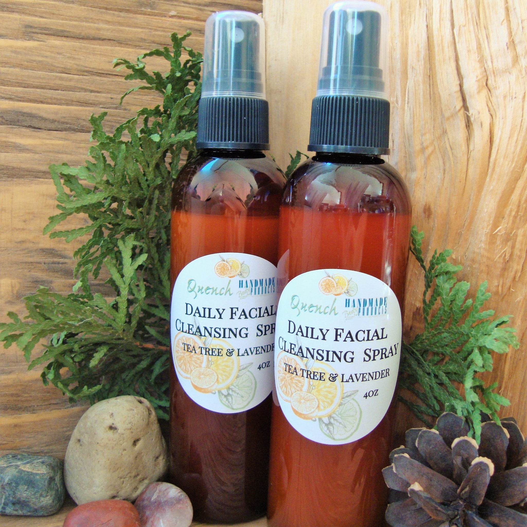 Facial Cleansing Spray bottles with brown liquid, black spray tops, and white labels with text and illustrations, "Quench" brand