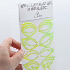 Face and body stickers with green and yellow holographic design, Vex Beauty brand packaging held by hand