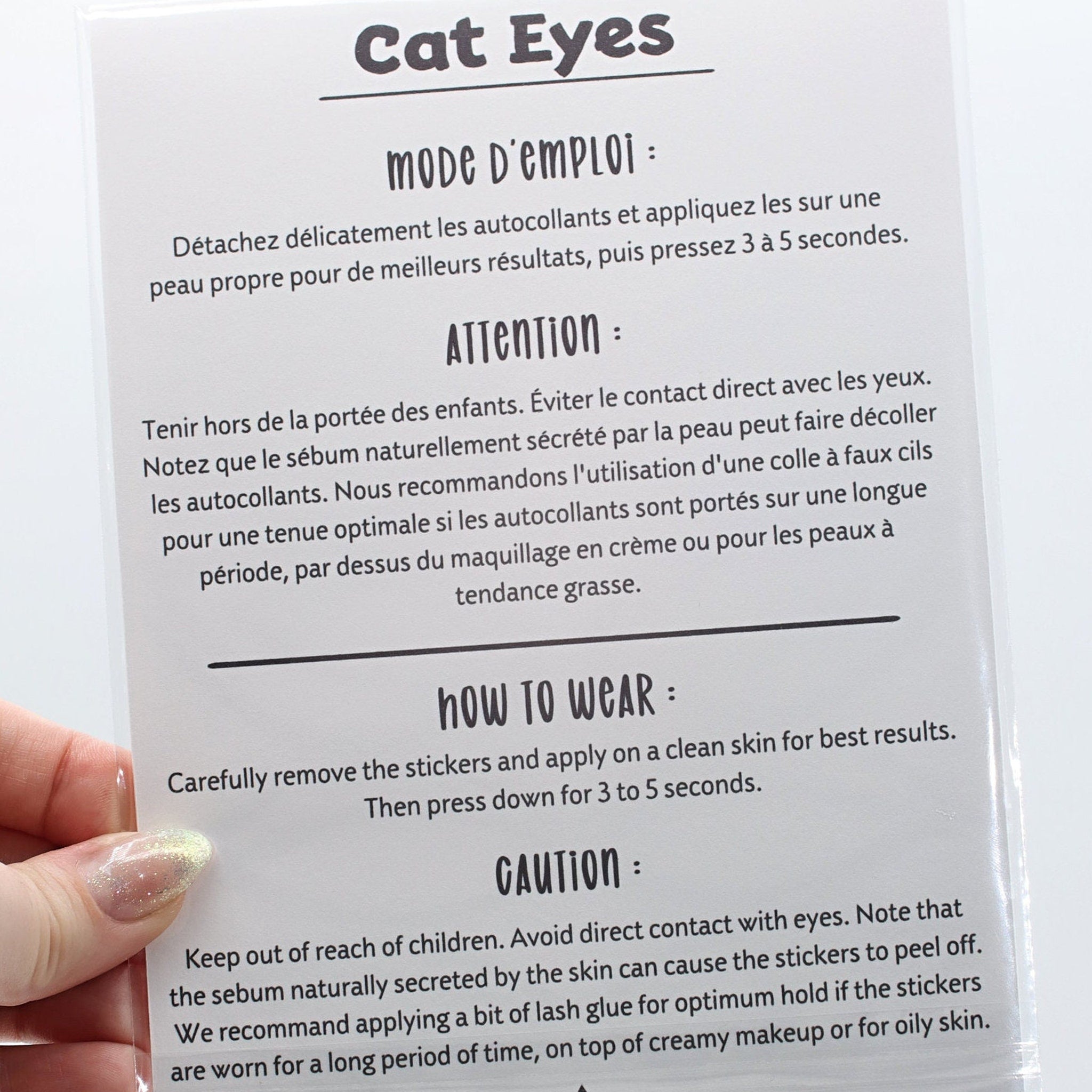 Cat Eyes instructions in white and black text on a clear plastic sheet, held by a hand