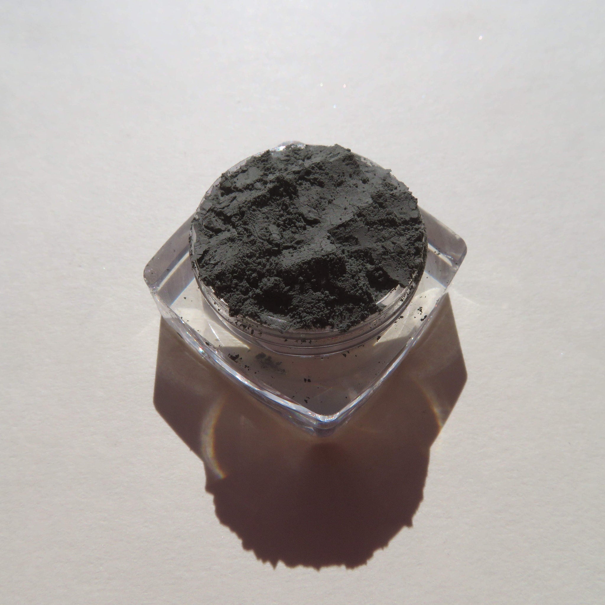 Open jar of dark matte green tea mineral eyeshadow with loose powder texture and mica shimmer