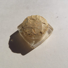 Glitter eyeshadow pot with gold color, clear container, and textured surface