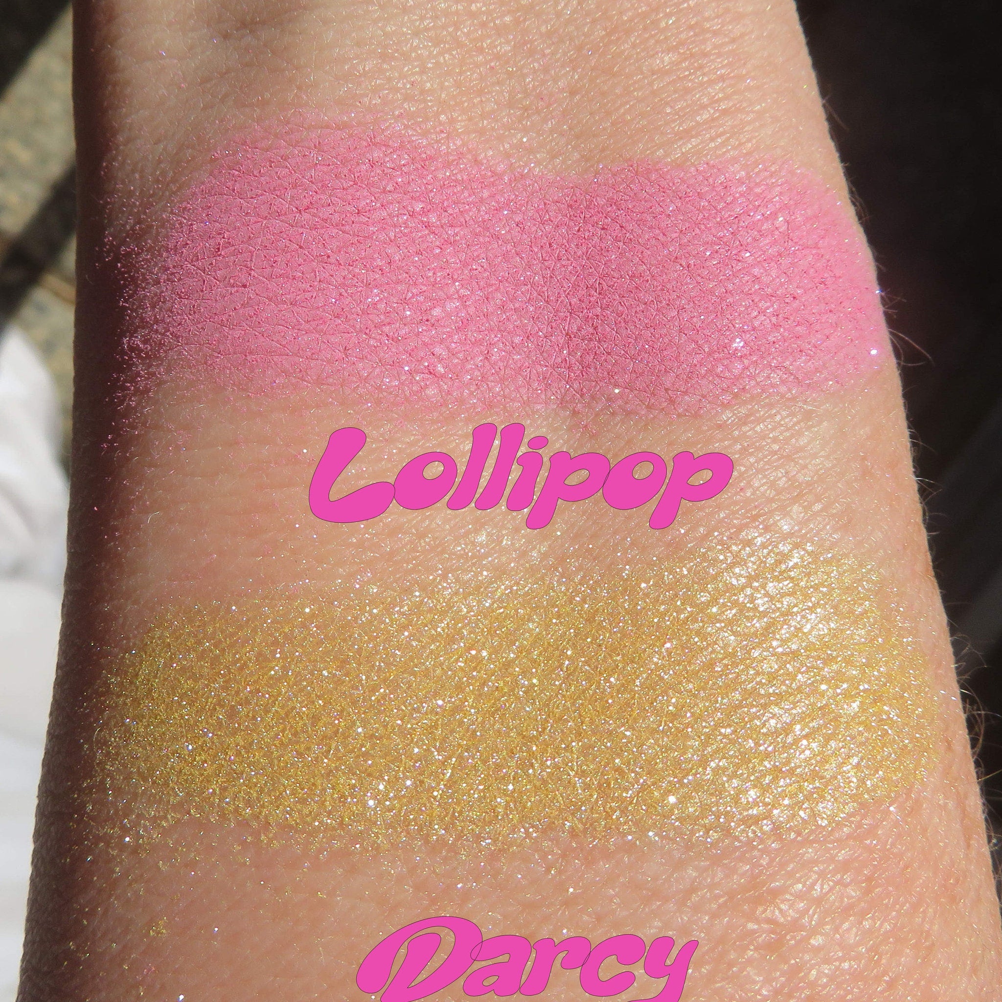 Makeup swatches of pink and gold glitter eyeshadow on skin, with "Lollipop" and "Darcy" text
