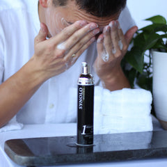 Facial cleanser bottle black and silver with white foam on face, Menceutical brand