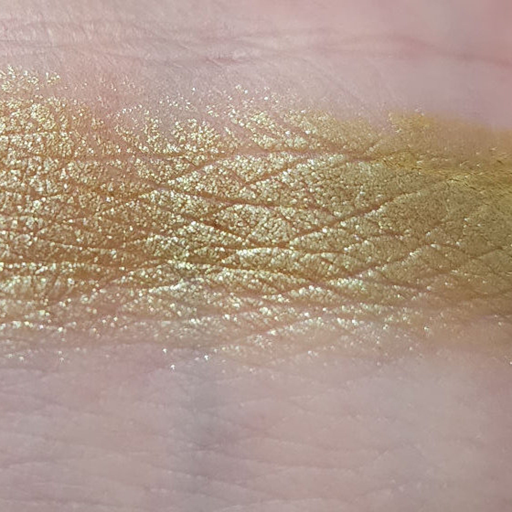 Close-up of fingertips applying shimmery emerald green eyeshadow from the palette onto eyelid