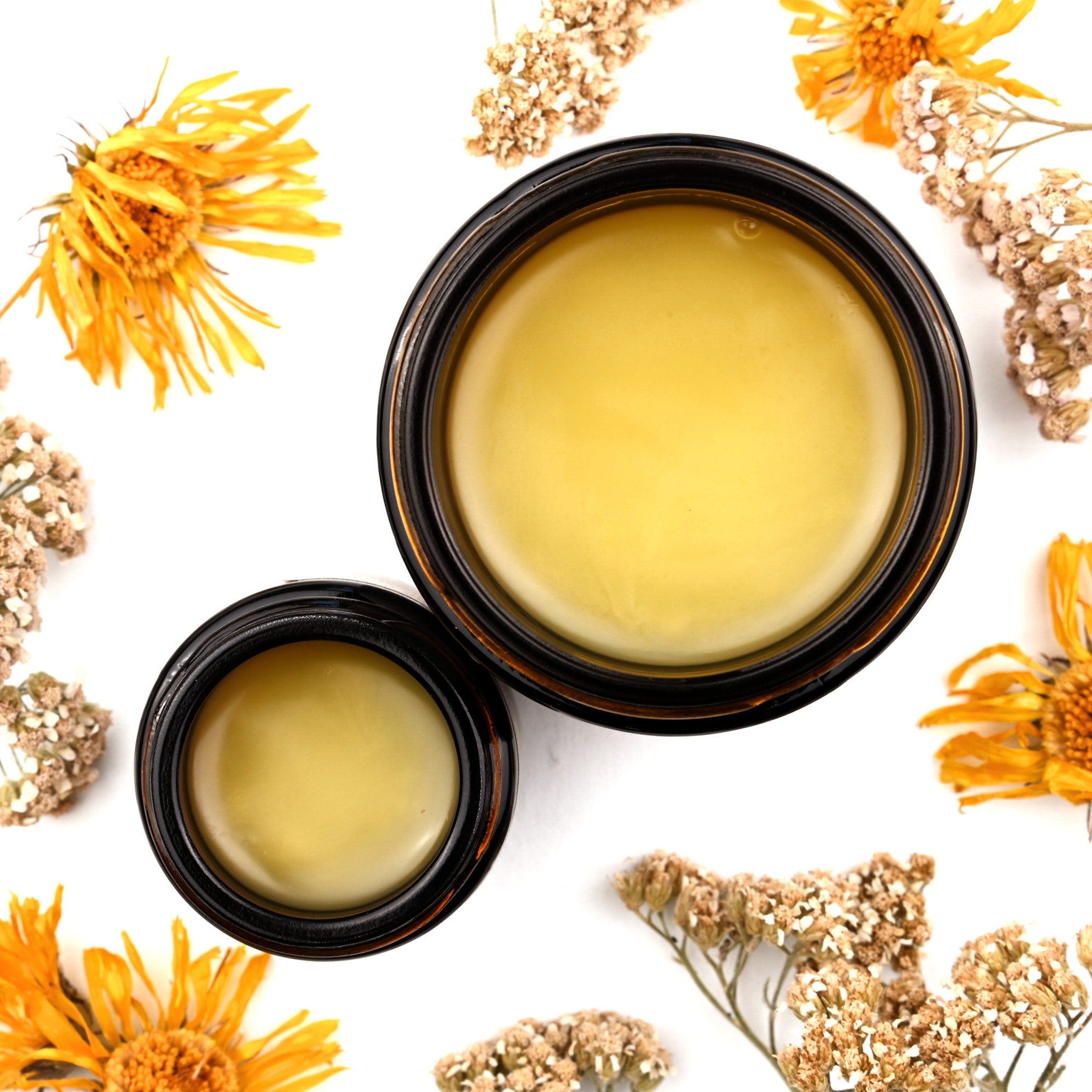 Yellow balm in dark brown jars with dried flowers and white background