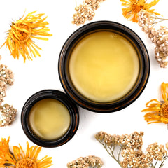 Yellow balm in dark brown jars with dried flowers and white background
