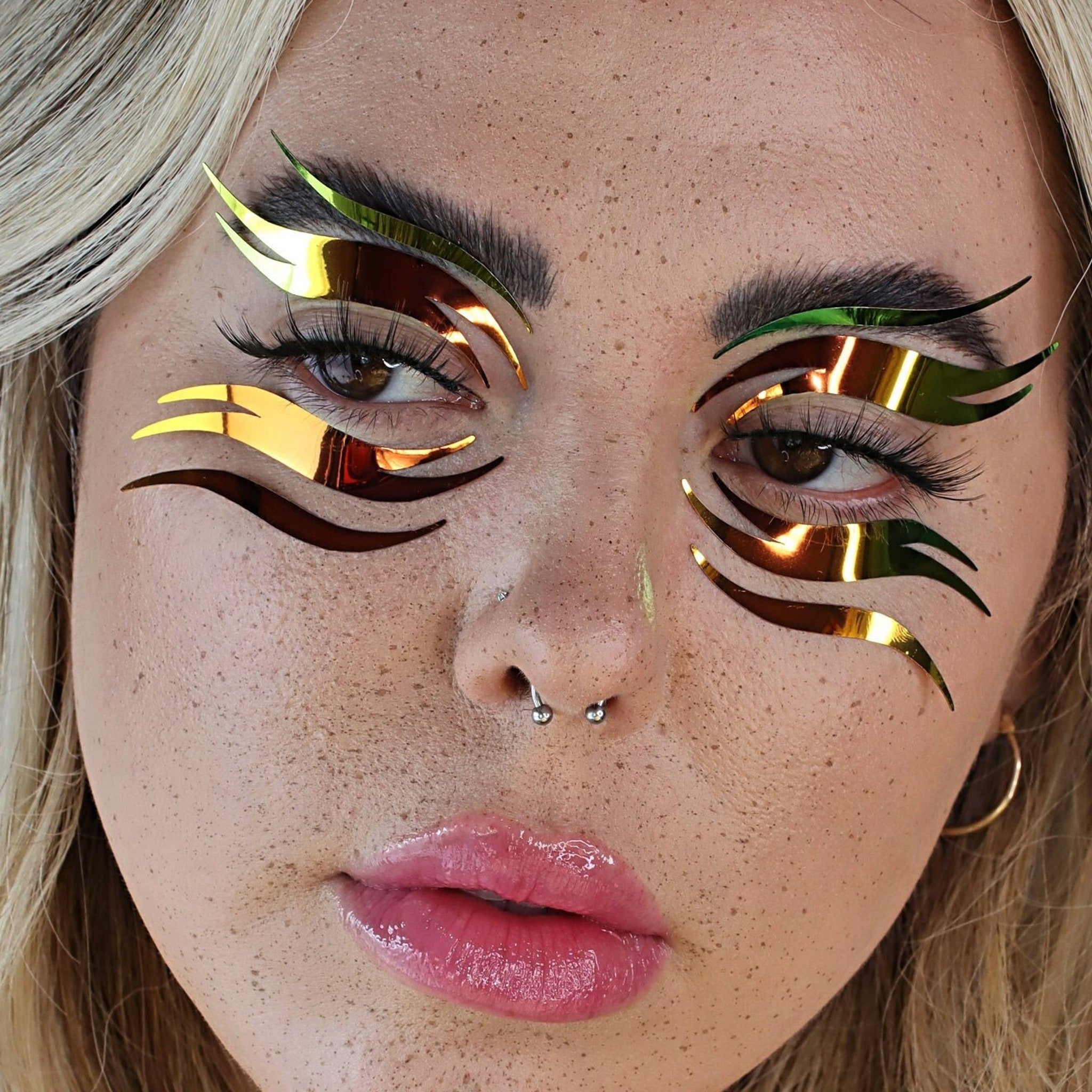 Eye makeup with gold and green metallic accents applied to model's eyes