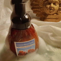 Facial cleanser bottle with brown liquid, black pump, and white label in foam