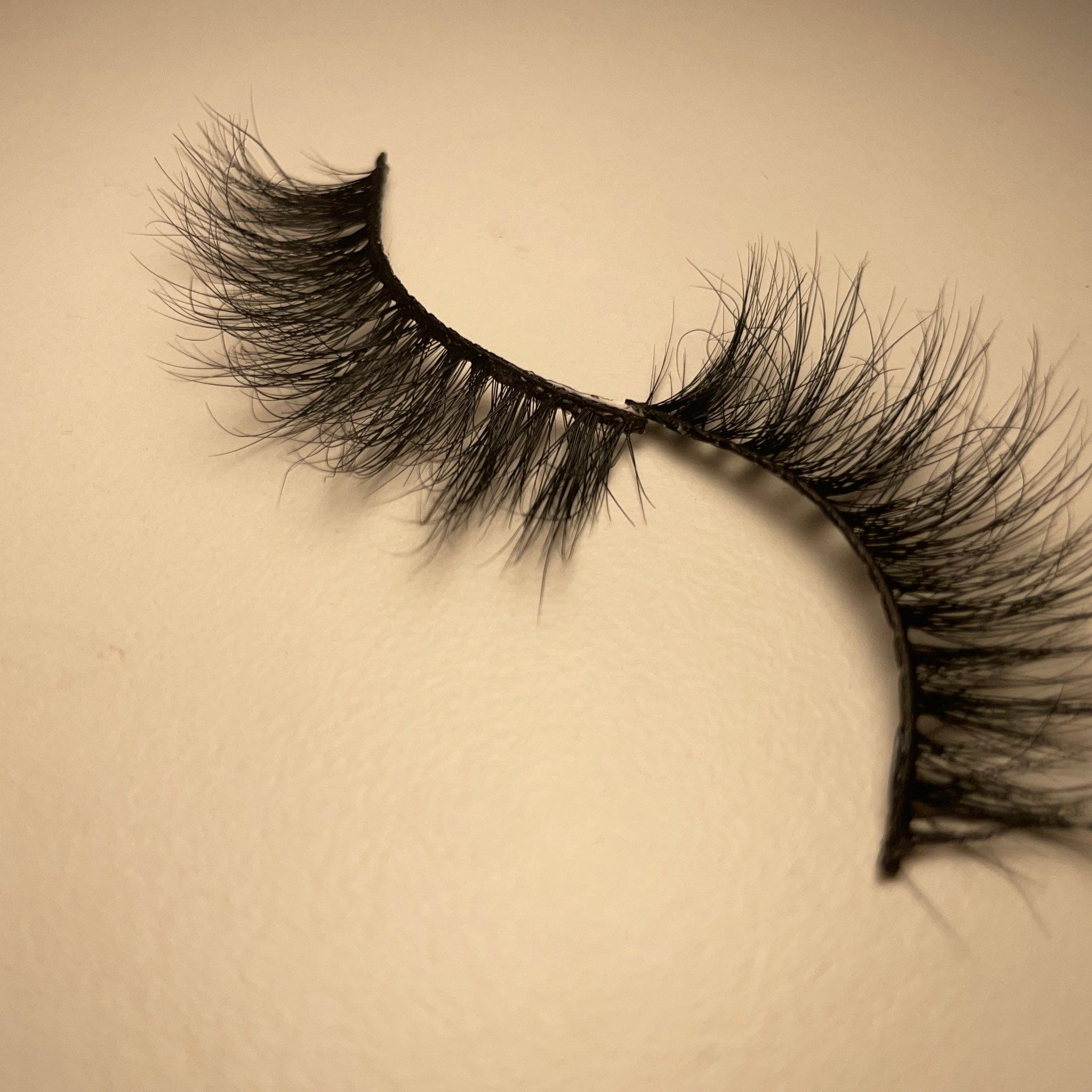 False eyelashes with black synthetic fibers and curved style on beige background