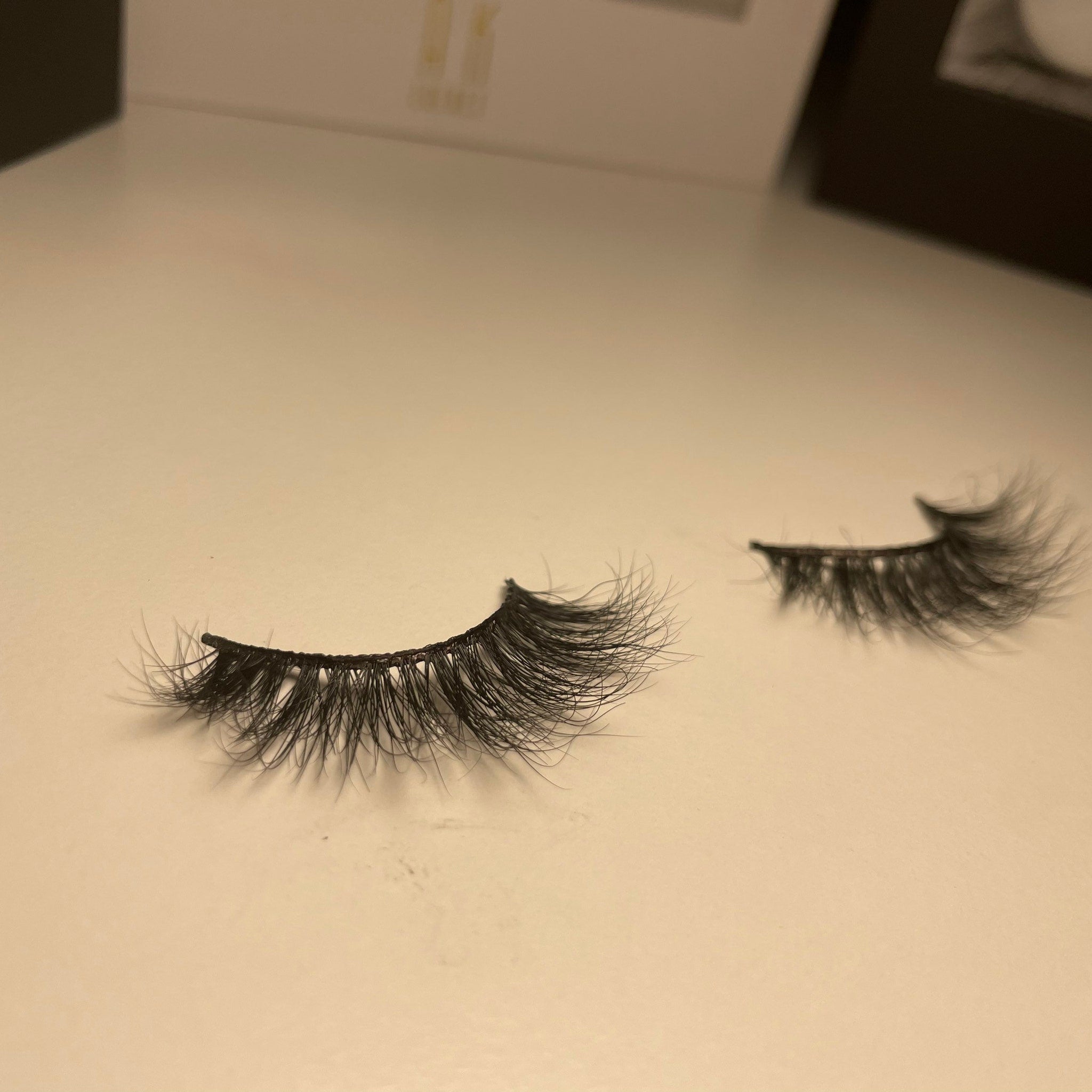 False eyelashes with black synthetic fibers on a light surface, curved style