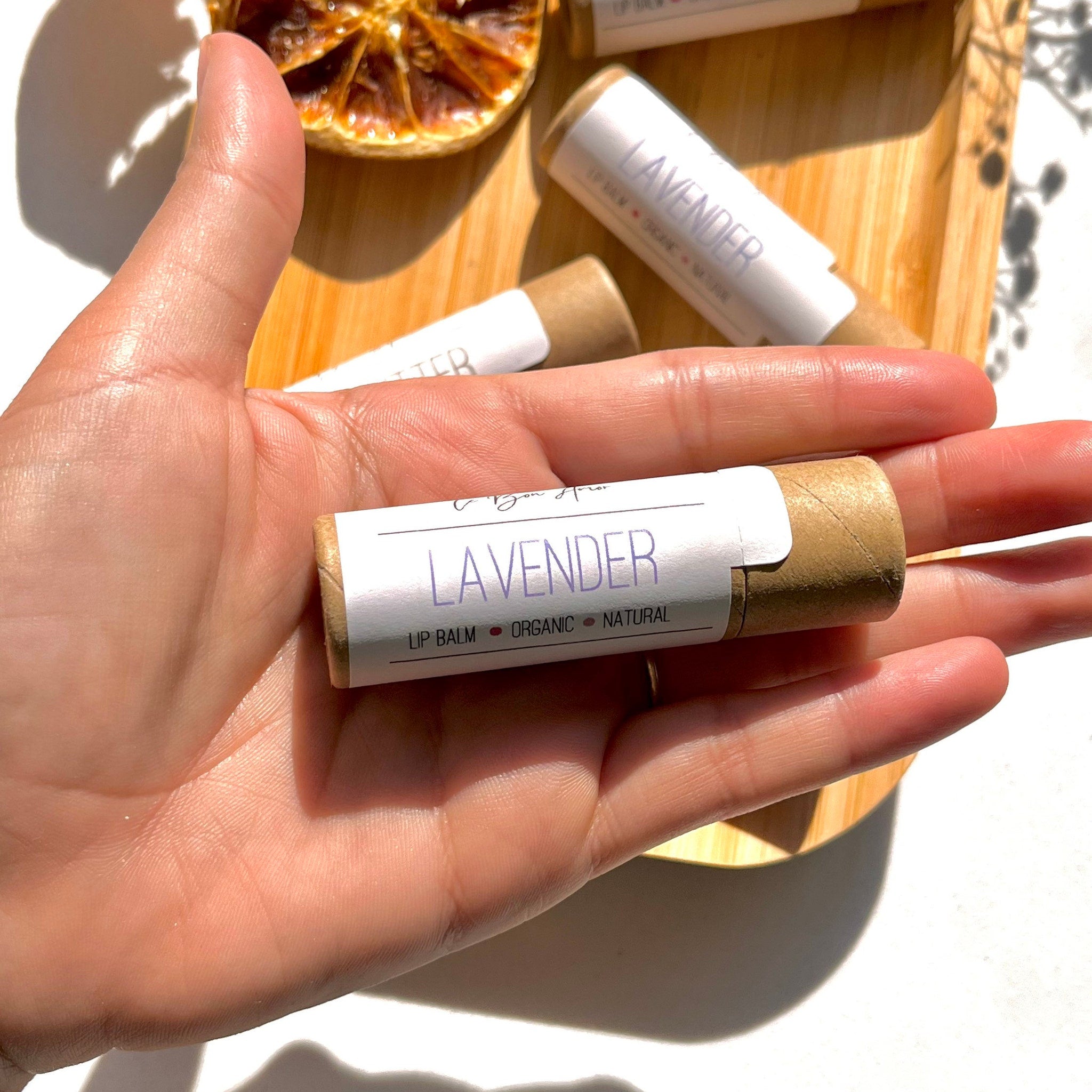 Lavender lip balm with white label, brown paper tube, held in hand