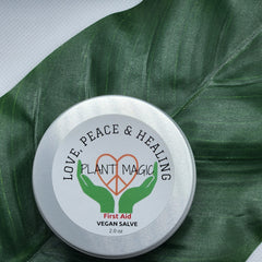 Vegan salve tin with silver metal, white label, and green leaf background