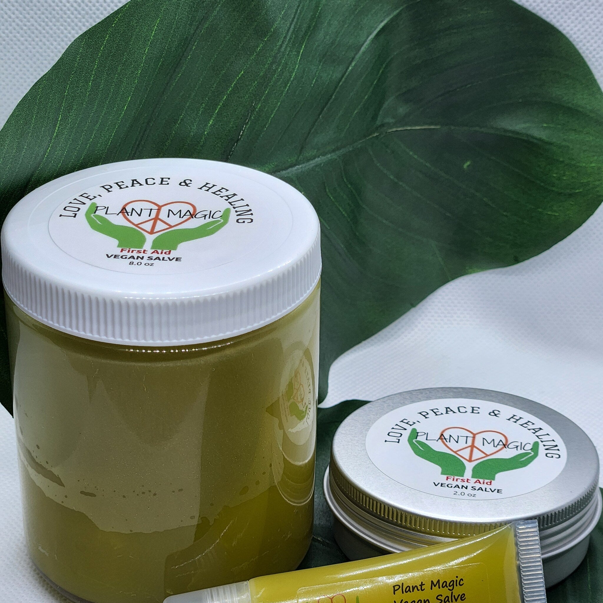 Vegan salve jars in green and silver with white lids, Plant Magic brand text visible