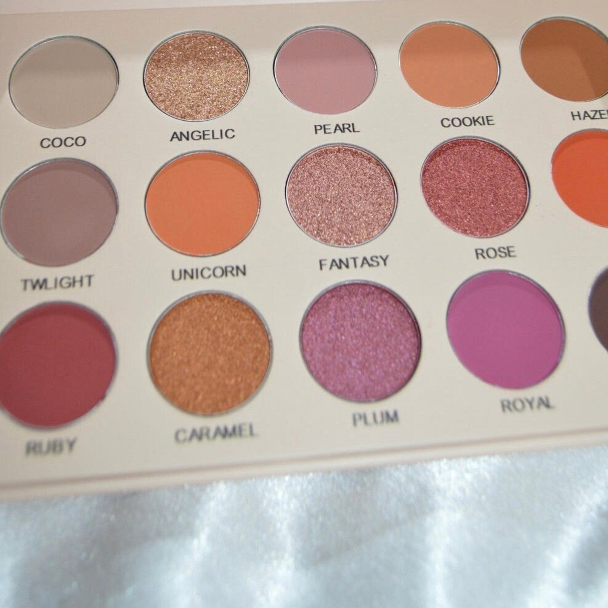 Front view of eye shadow palette showing matte and shimmer shades in warm neutral tones with sleek black compact