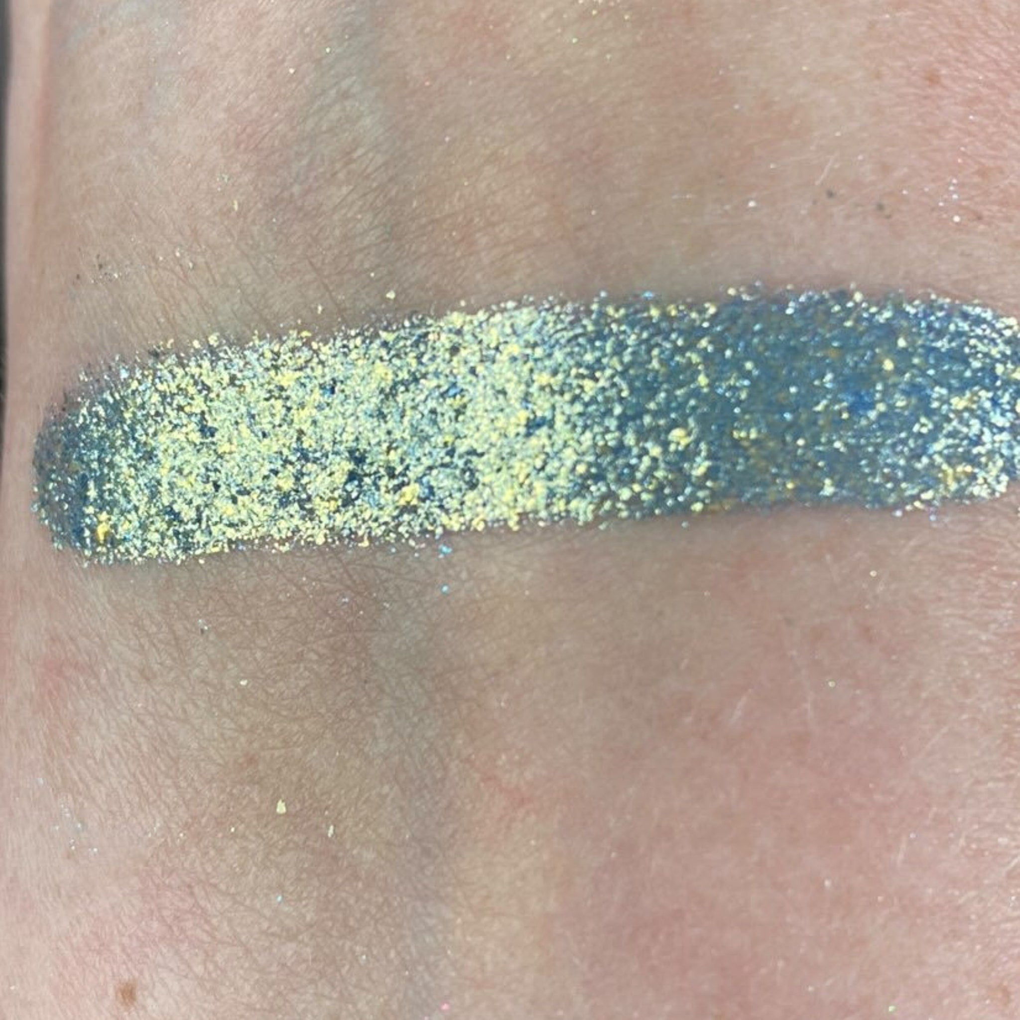 Close-up of shimmering holiday eye shadow palette showing gold and silver sparkle textures in circular pans