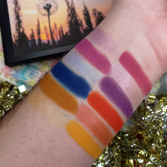 Eyeshadow swatches with various colors on arm, including pink, blue, orange, and purple