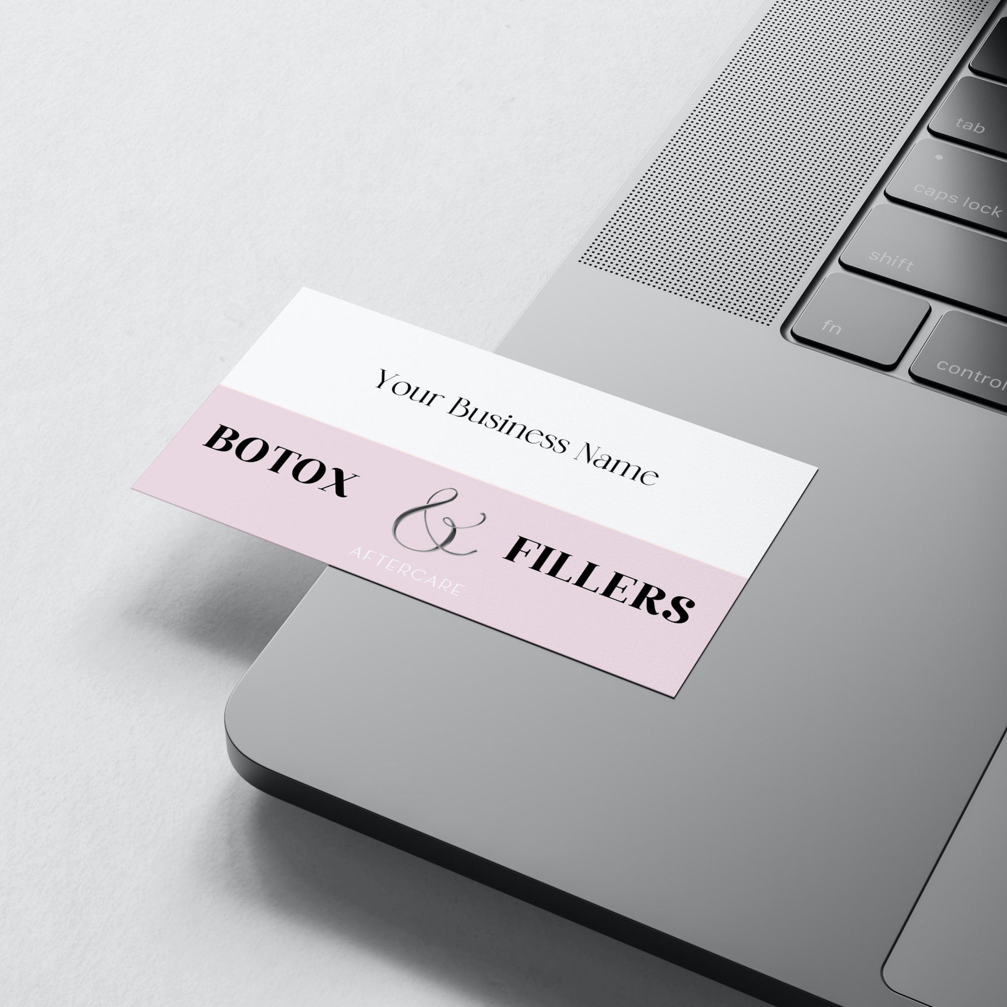 Business card with white and pink color, text "Botox & Fillers" on a laptop surface