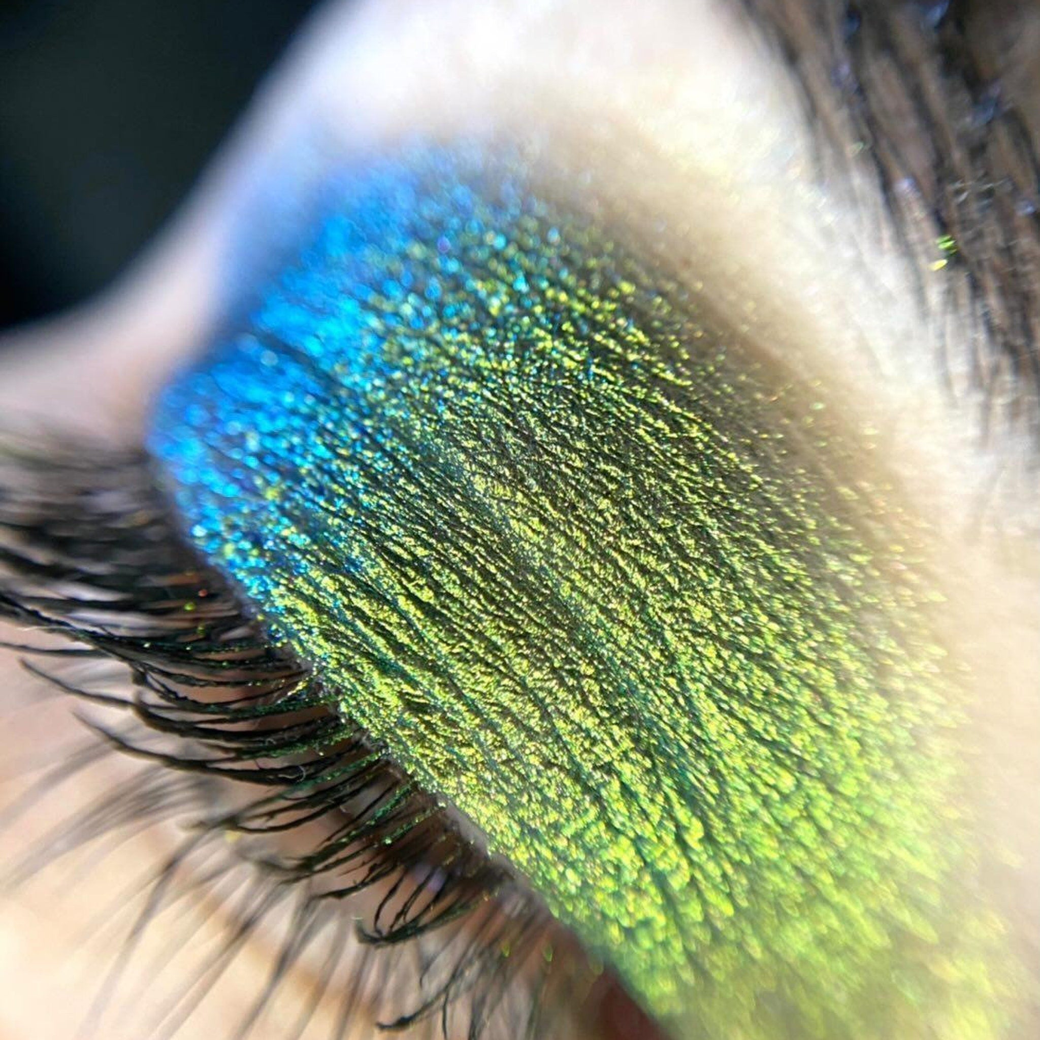 Close-up of loose multi-chrome eye shadow pigment showing shimmering color shift in vibrant hues
