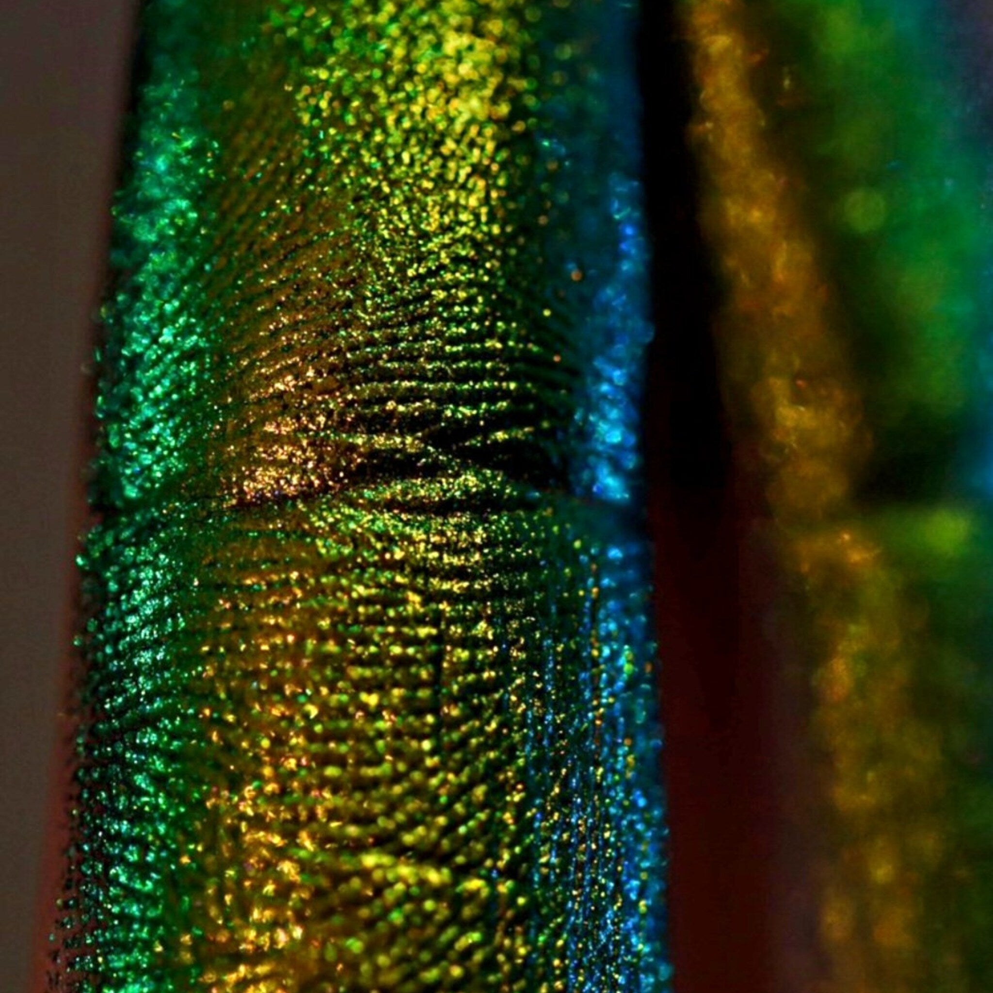 Side view of loose multi-chrome eye shadow pigment showing shimmer particles catching light