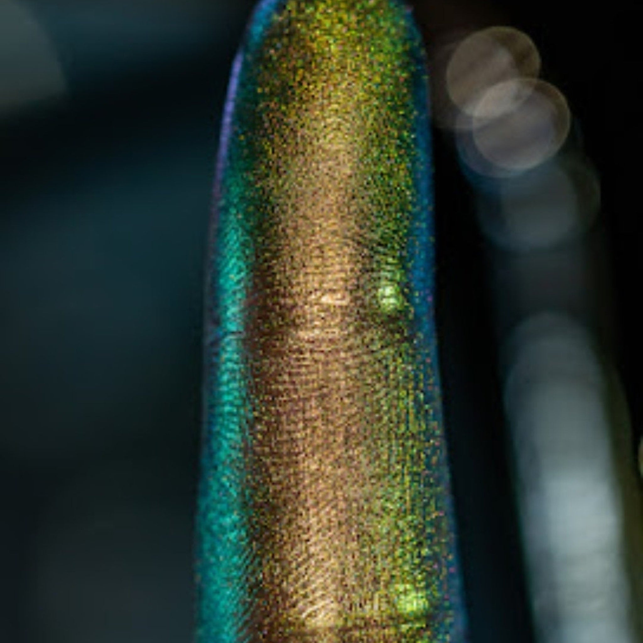 Hand applying multi-chrome loose pigment eyeshadow with fingertip, showing shimmer payoff on eyelid
