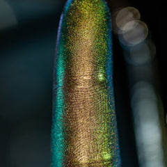 Hand applying multi-chrome loose pigment eyeshadow with fingertip, showing shimmer payoff on eyelid