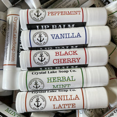 Lip balm tubes with white, color-coded labels, Crystal Lake Soap Co. branding, various flavors