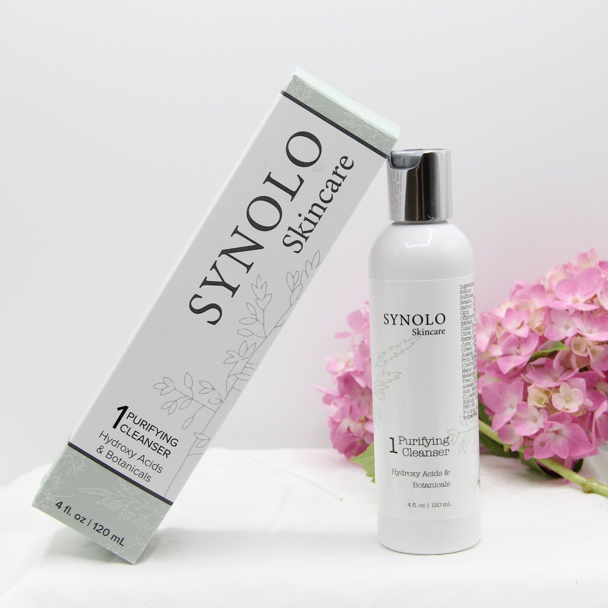 Purifying cleanser bottle and box, white with black text, SYNOLO Skincare brand, with floral pattern