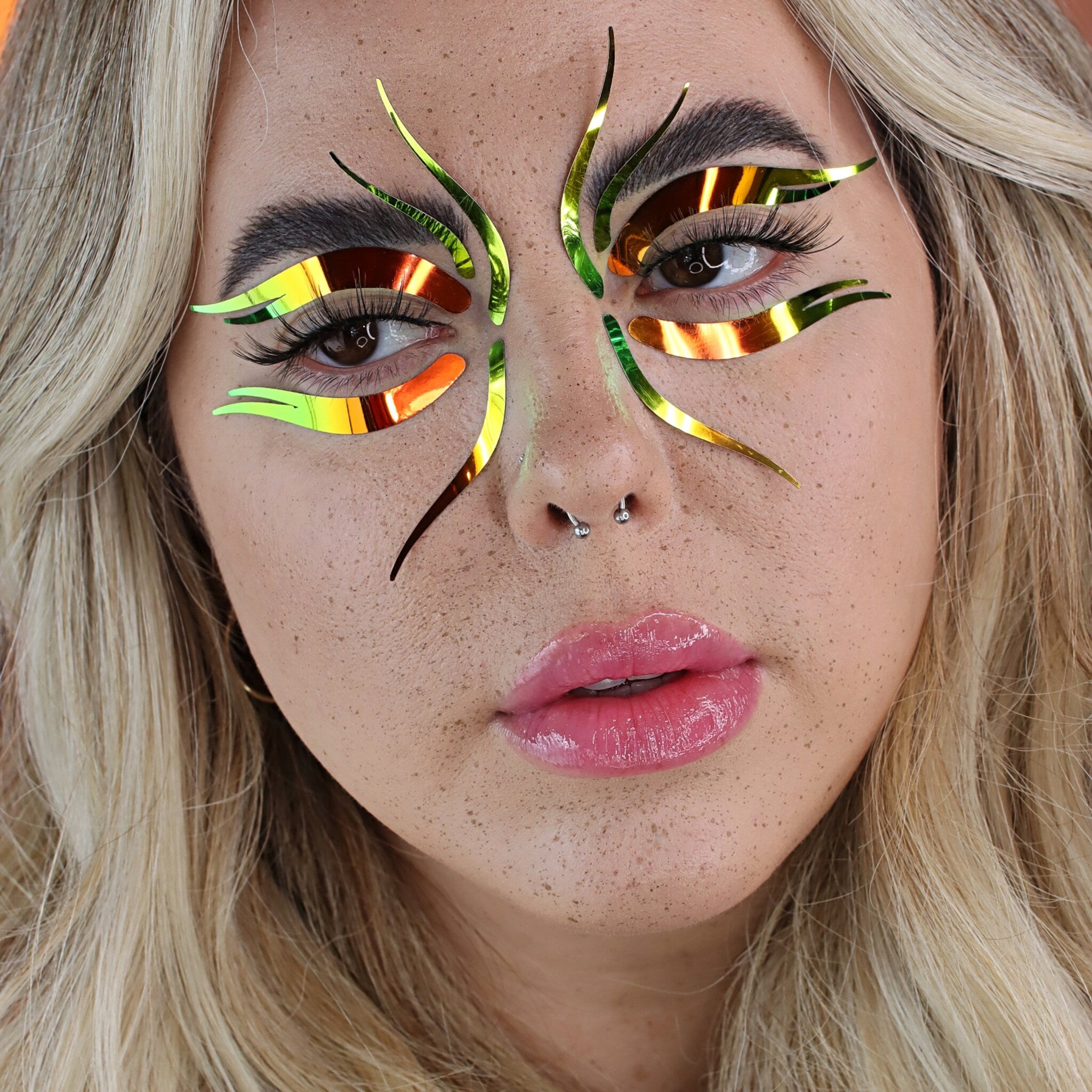Eye makeup with green and orange iridescent accents, applied on face
