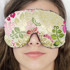 Travel eye mask with floral brocade pattern, cream and pink, worn on face