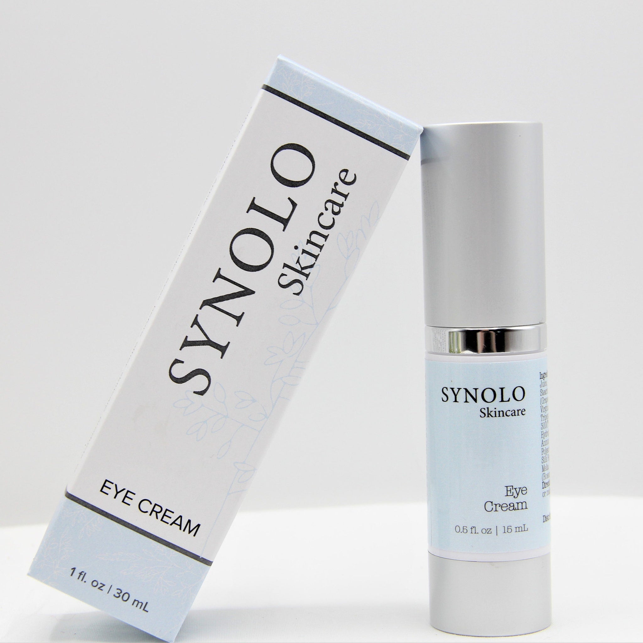 Eye cream product with white and light blue packaging, SYNOLO Skincare brand visible, silver cap