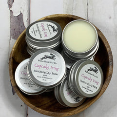 Lip balm tins, silver metal containers, Wilde Hare Soap Co. branding, wooden bowl