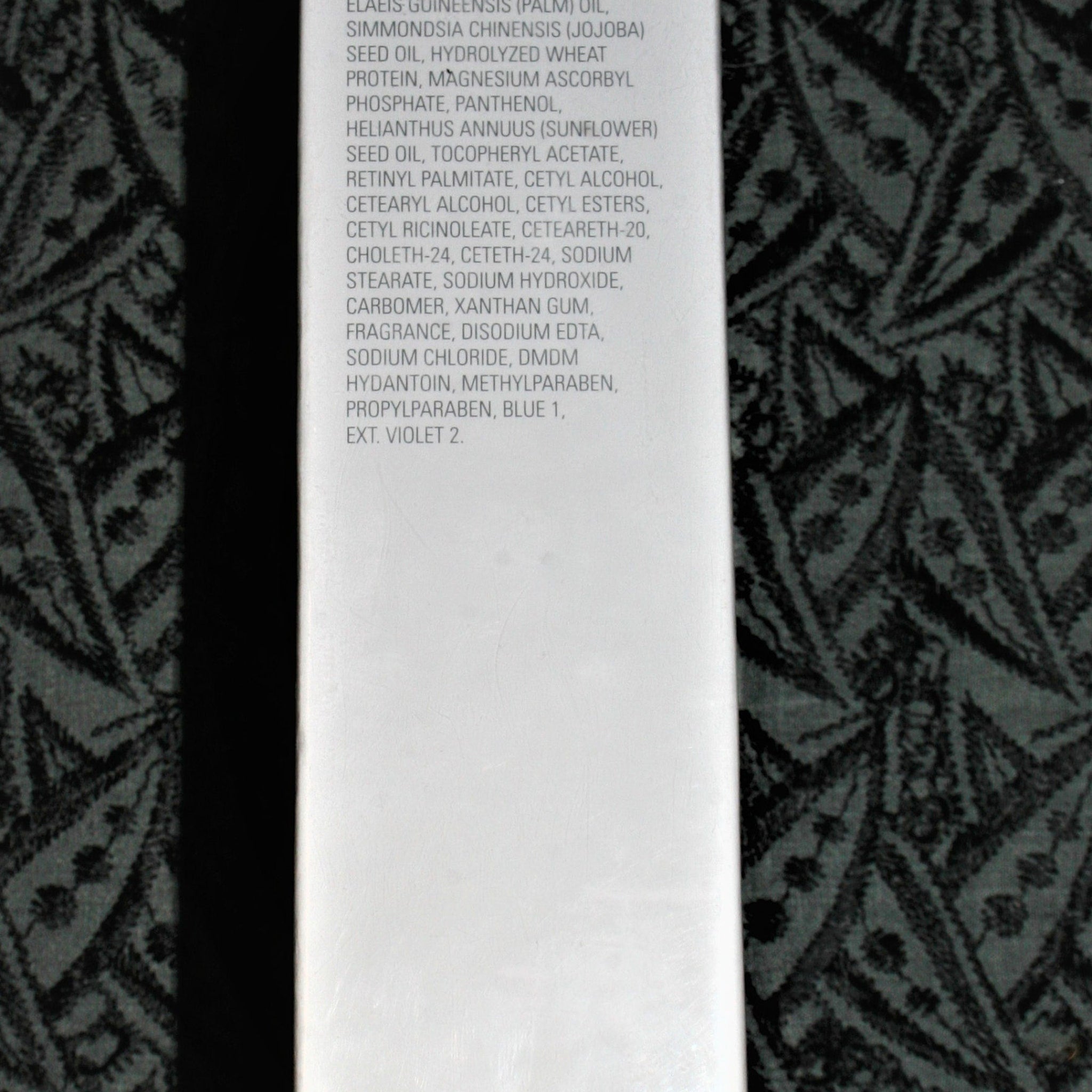White product ingredient list on a patterned black and gray background, vertical style
