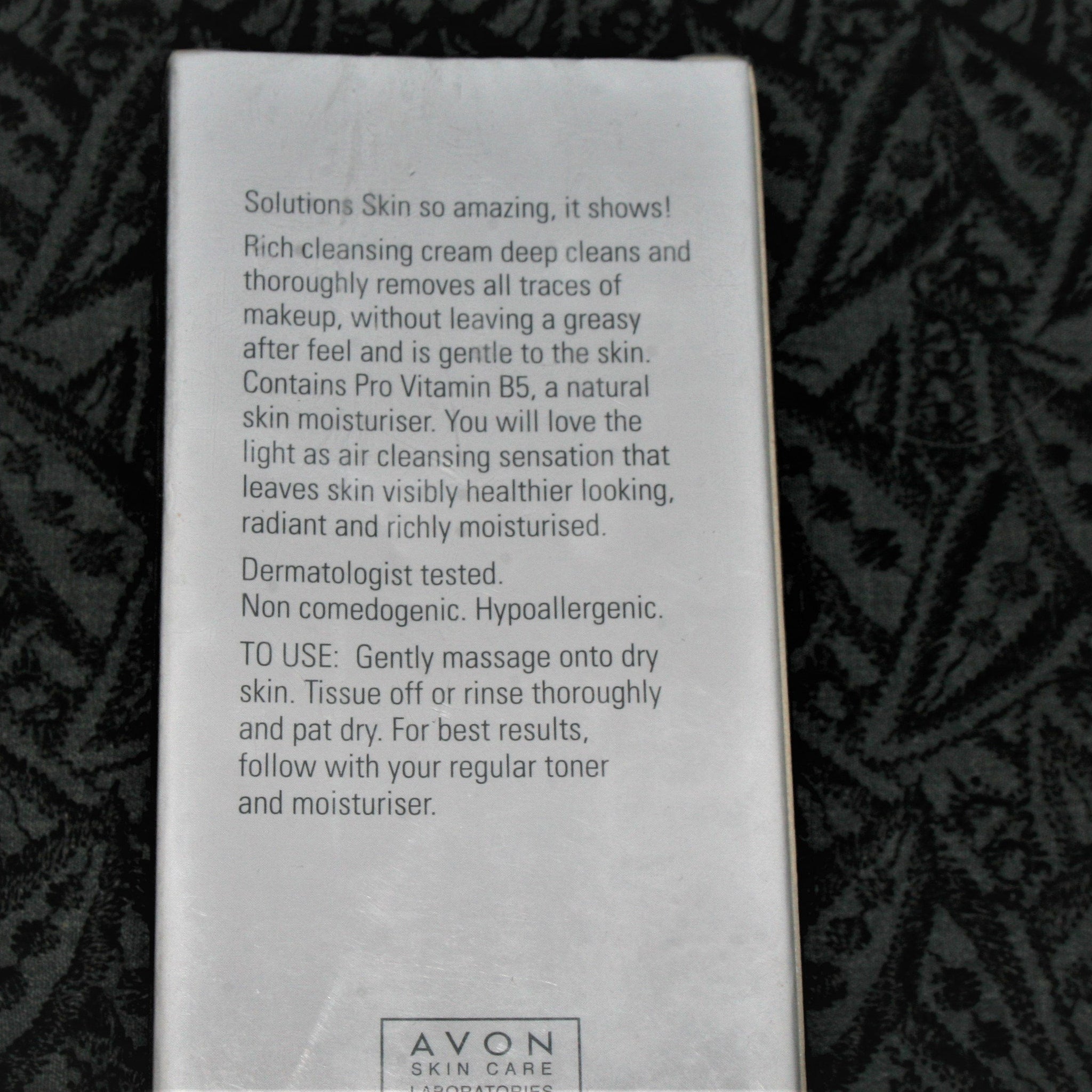 Avon skin care product box, white with black text, on patterned background.