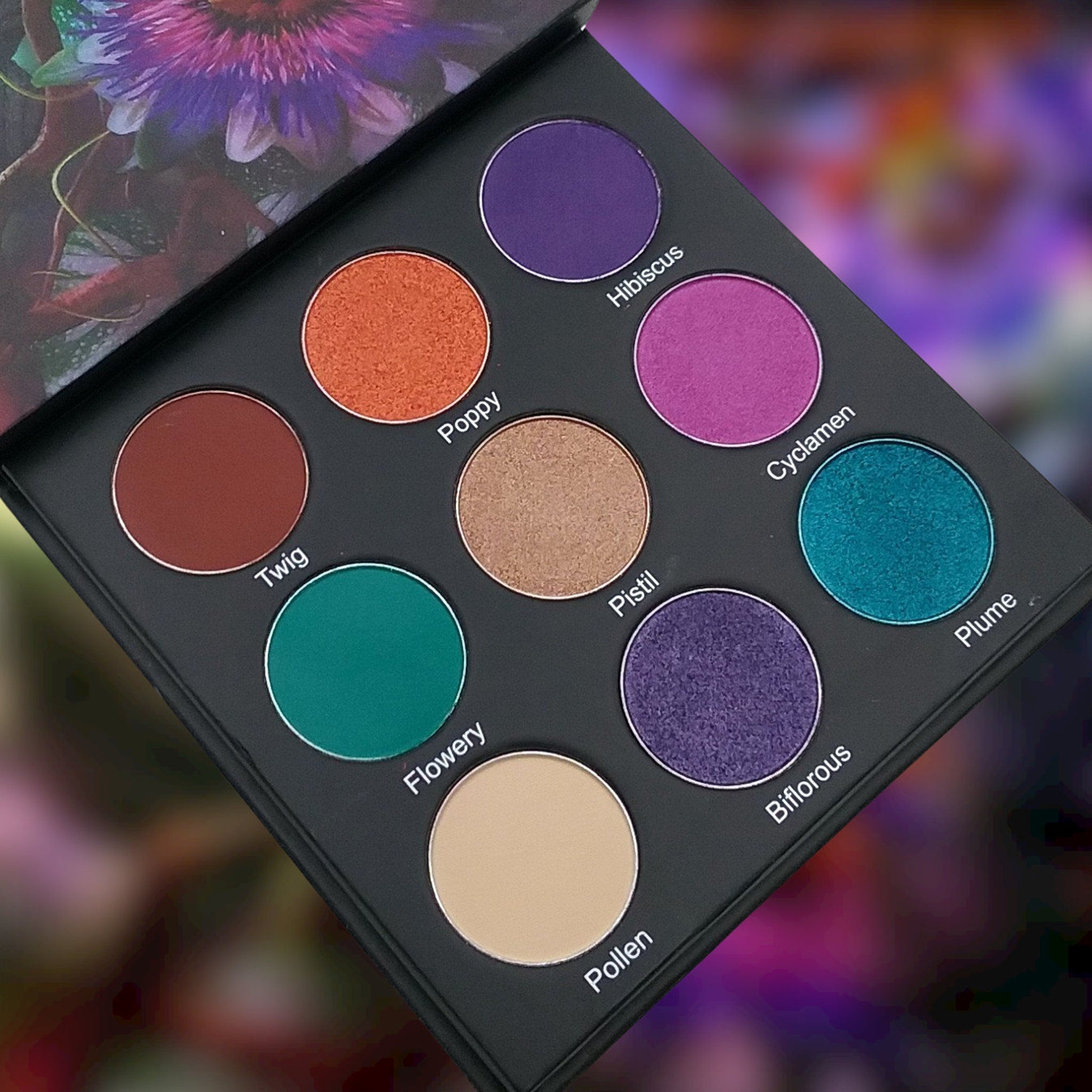 Eyeshadow palette with multiple colors including purple, orange, and green in a black compact case