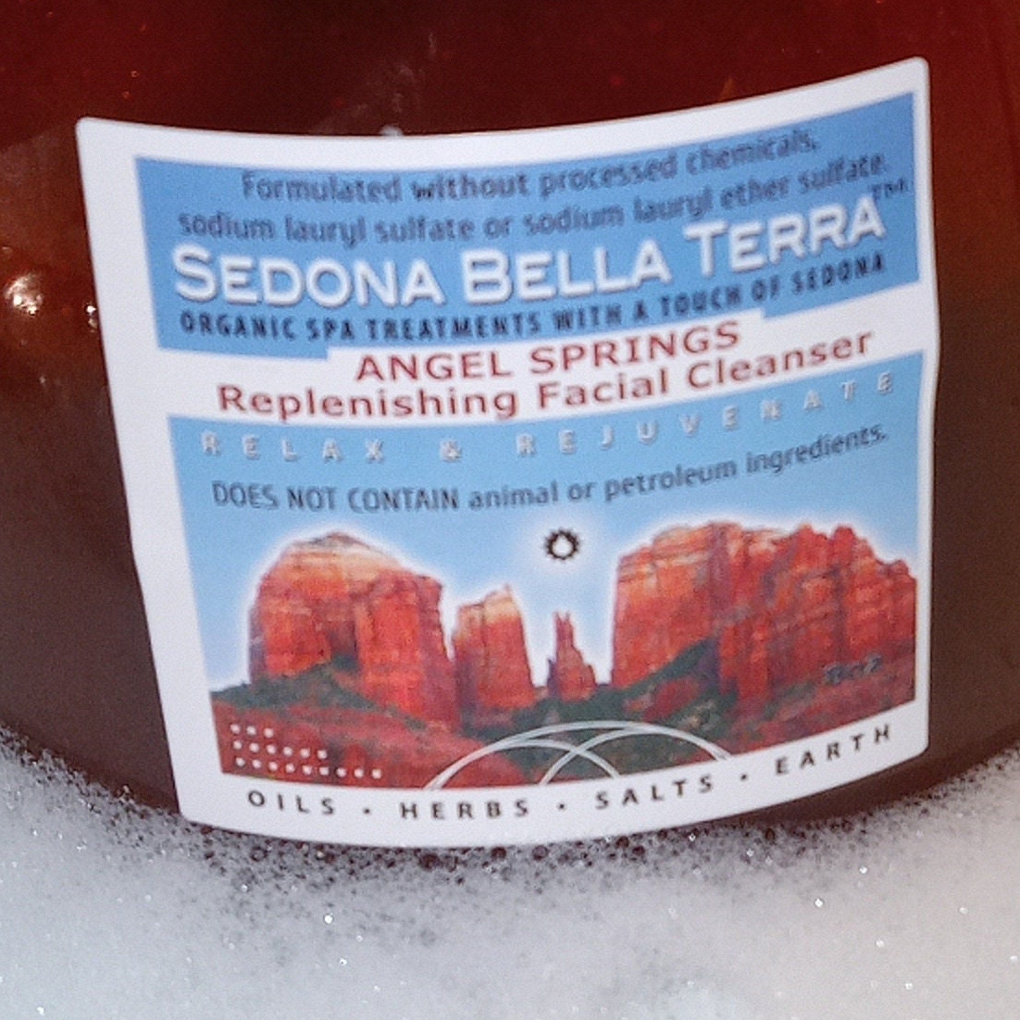 Facial cleanser label with blue and white text, red landscape art, and "Sedona Bella Terra" brand name