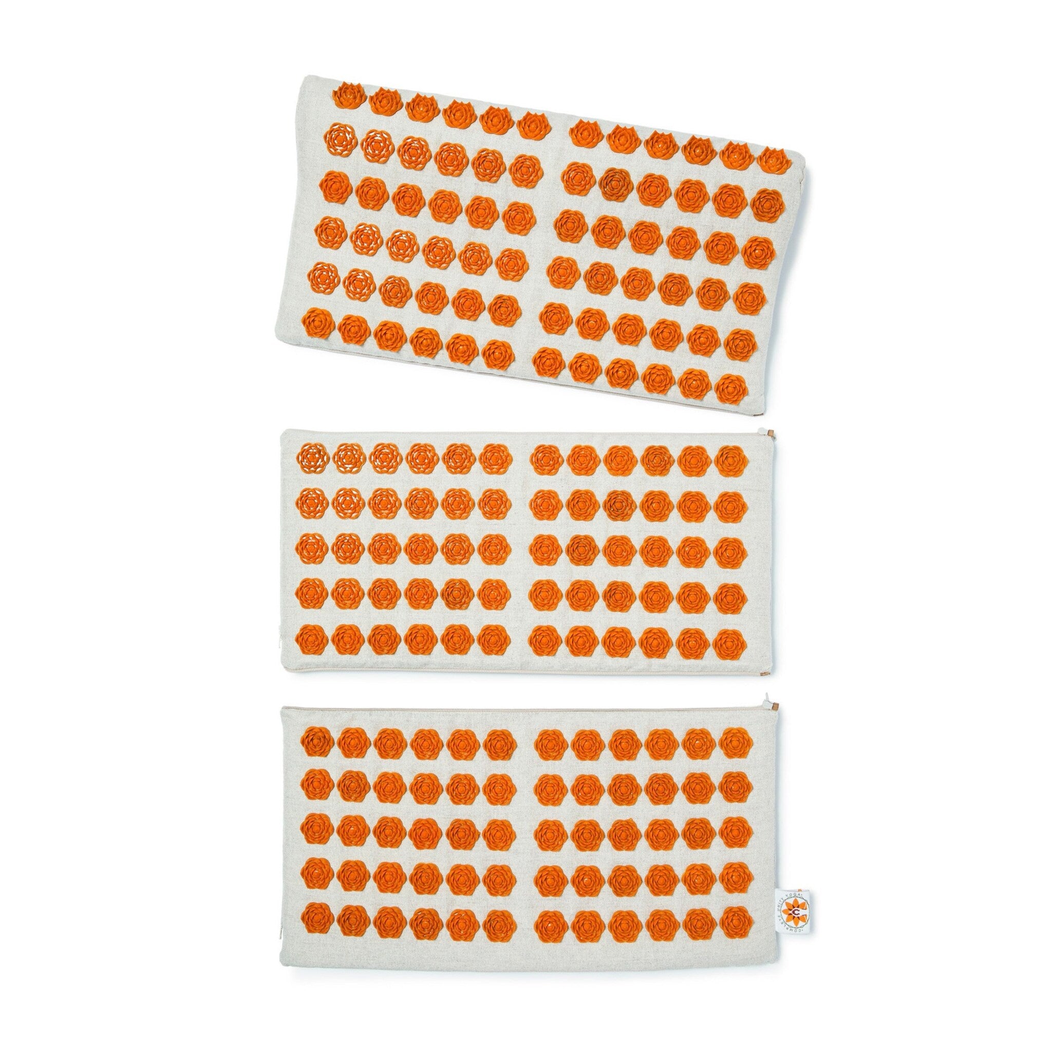 Acupressure mats with orange flower-shaped nubs on a light-colored fabric surface, stacked vertically