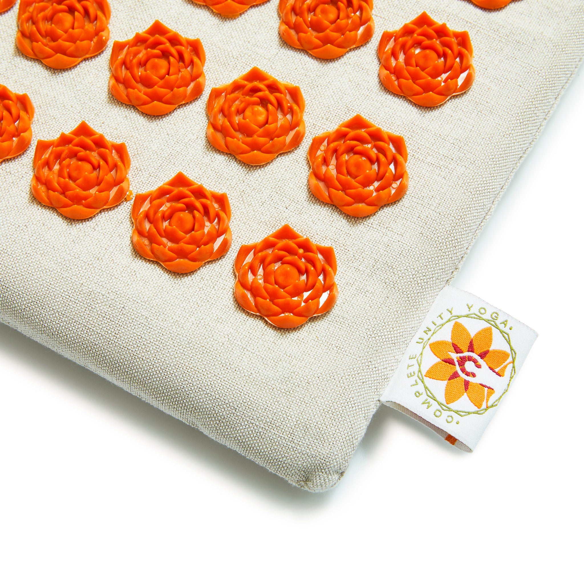 Acupressure mat with orange flower-shaped nodes on beige fabric, Unity Yoga brand tag visible