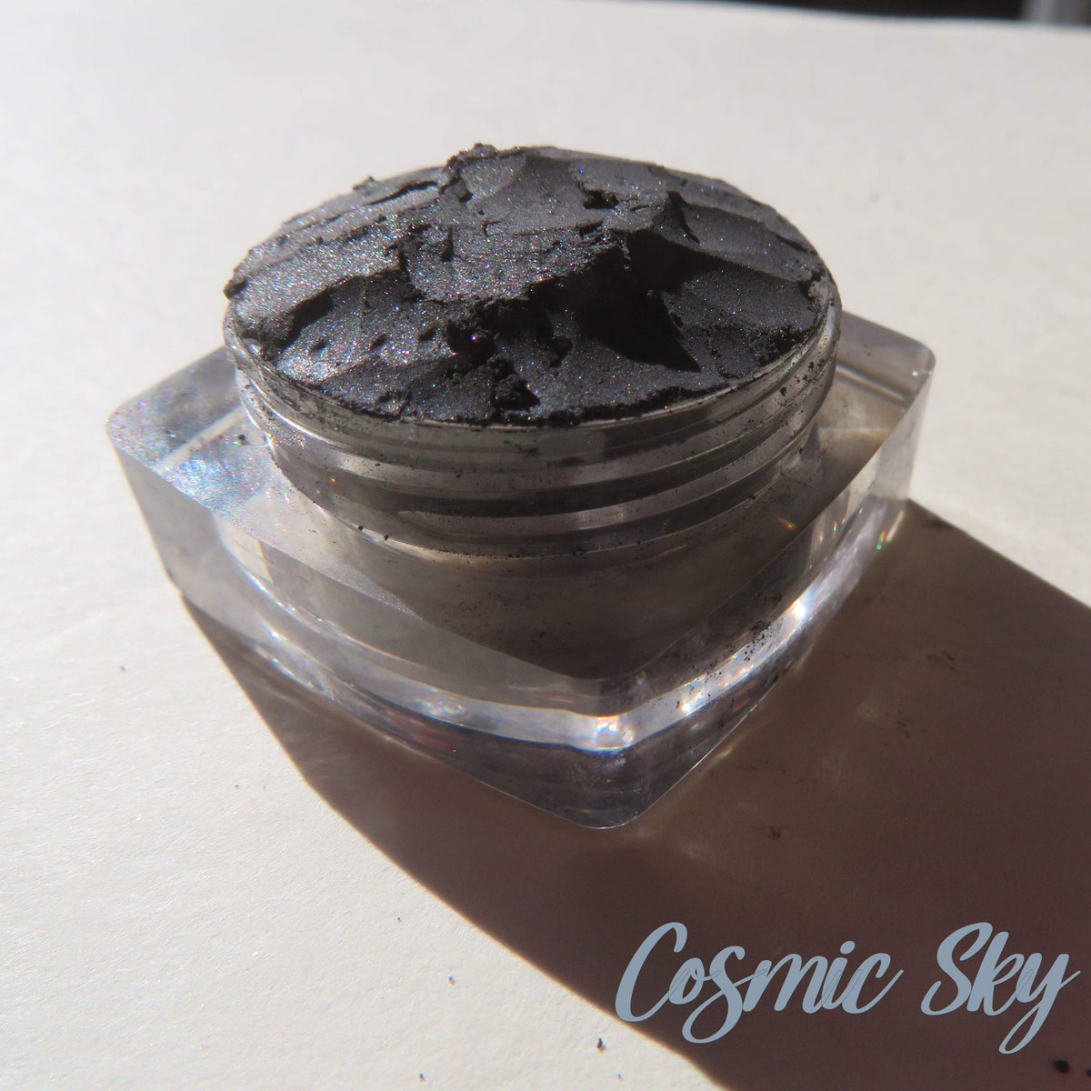 Black shimmer mineral eyeshadow in loose powder form with cosmic sparkle effect, vegan and cruelty-free