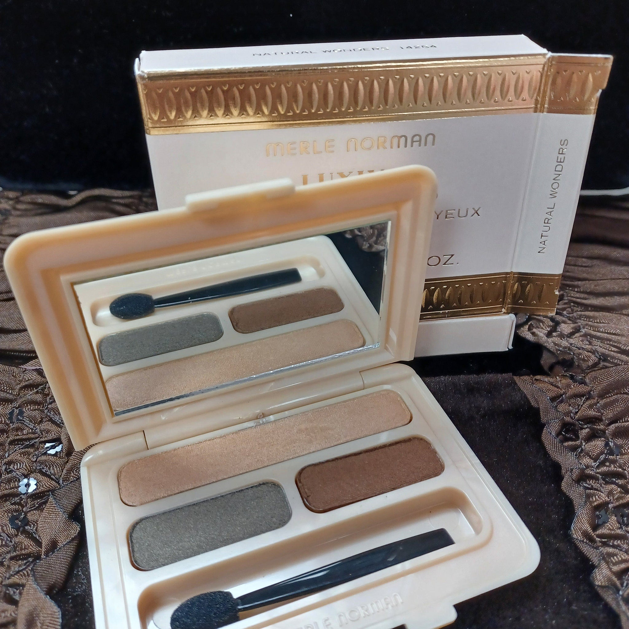 Eyeshadow palette with neutral colors, mirror, and Merle Norman branding.