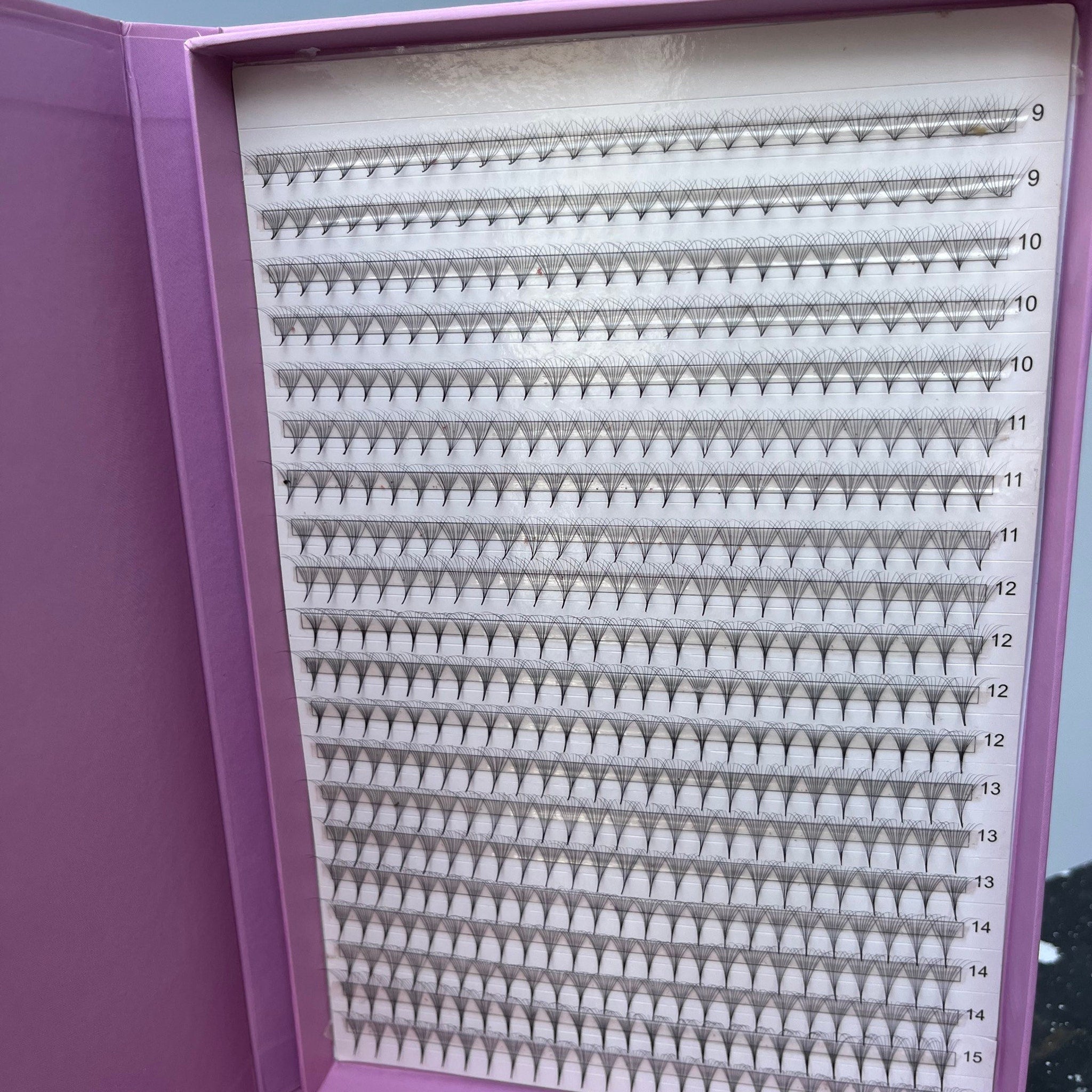 Eyelash extensions in a purple box with black fans and white backing, numbered for length