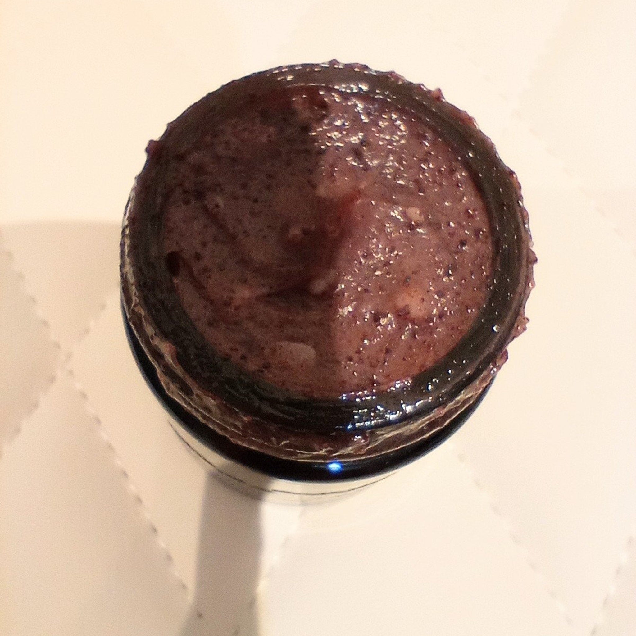 Smoothie in a dark glass jar, with dark purple color and textured surface, top-down view