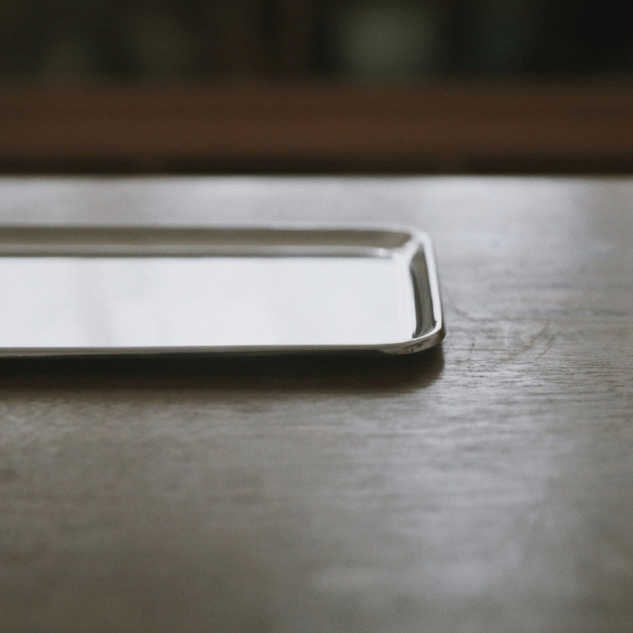 Silver rectangular tray with rounded corners on wooden surface