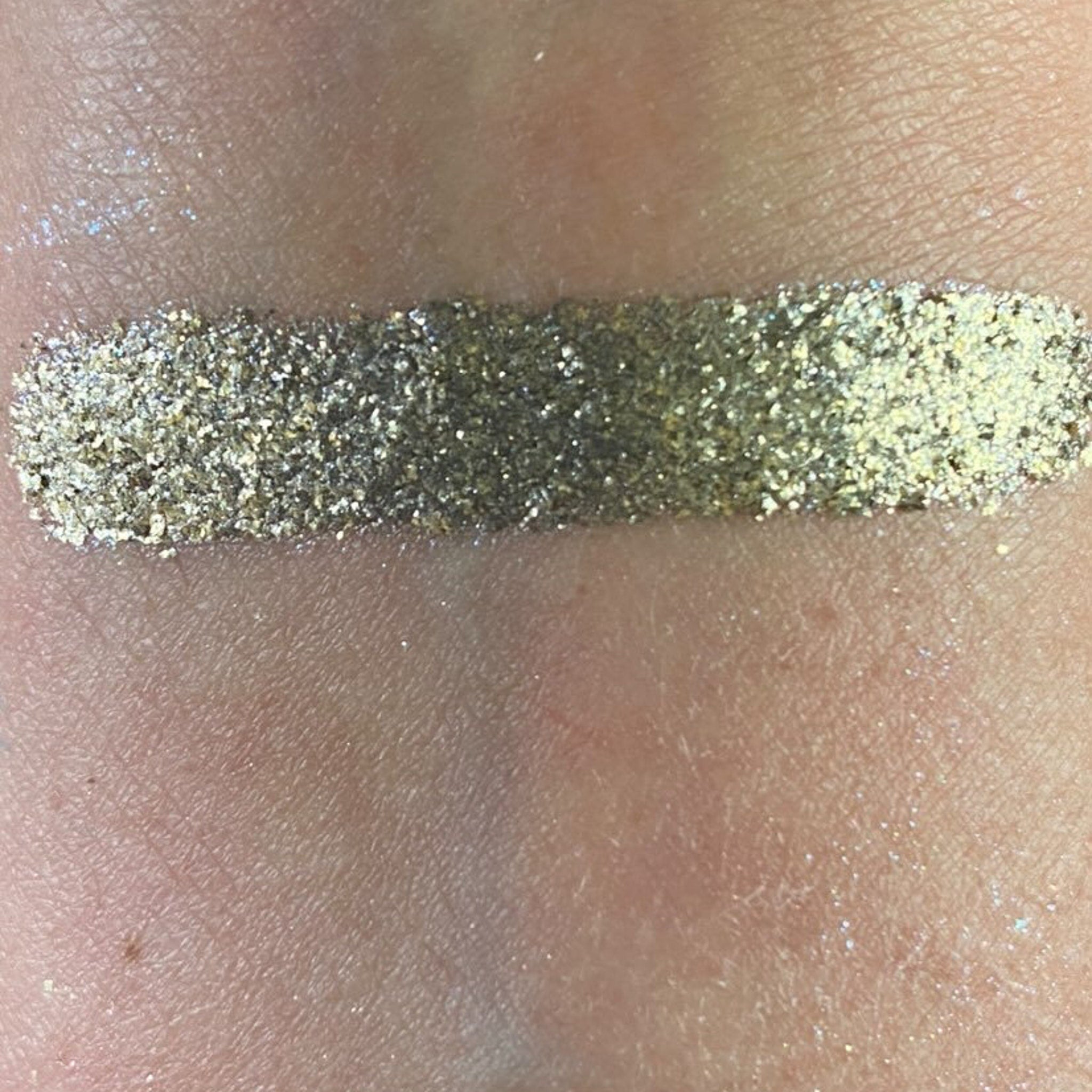 Hand applying shimmery silver eye shadow from palette to eyelid with brush