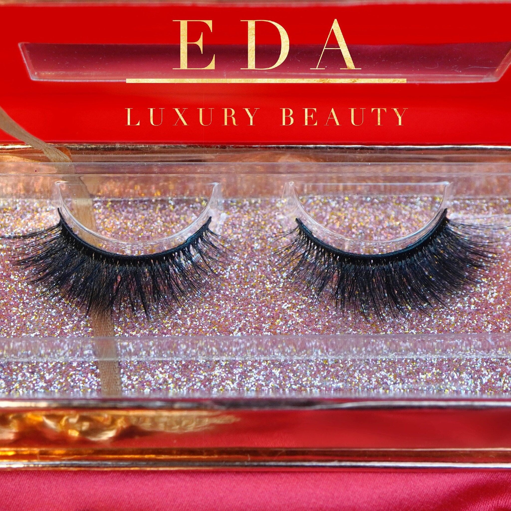 False eyelashes with black lashes, clear band, and EDA Luxury Beauty text on red box
