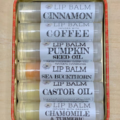 Lip balm tubes with white labels, clear plastic, and red tin container, newfashionsoapco.etsy.com text visible