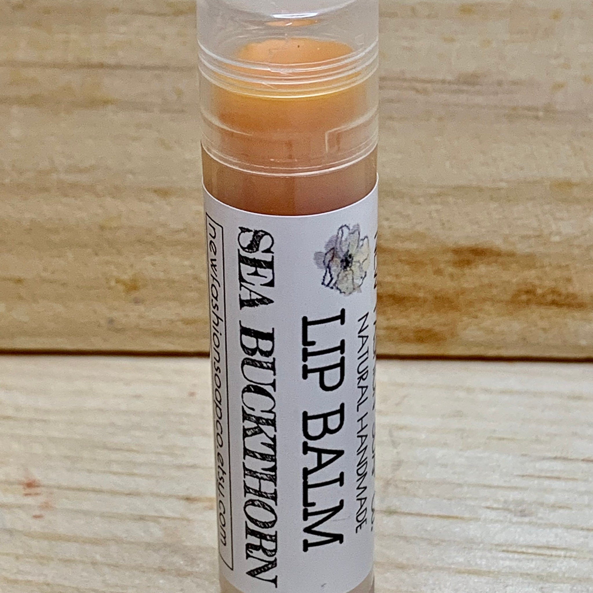 Lip balm tube with clear plastic, orange balm, and Sea Buckthorn label