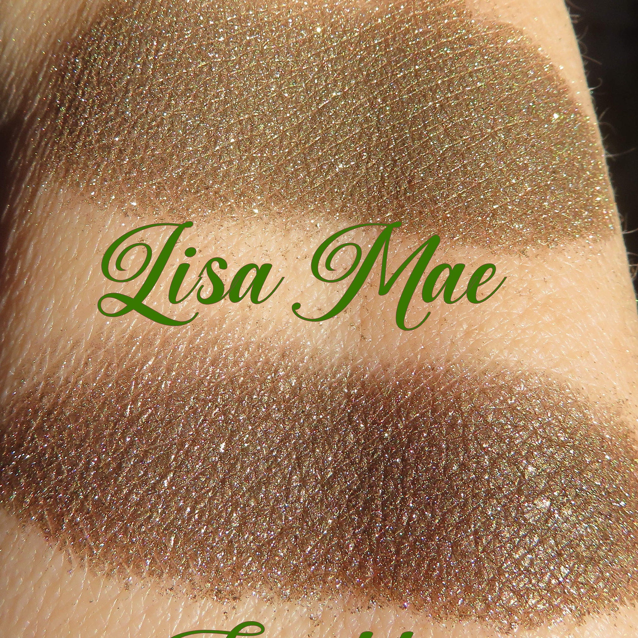Eyeshadow swatch with glitter, brown color, Lisa Mae brand name in green text on skin