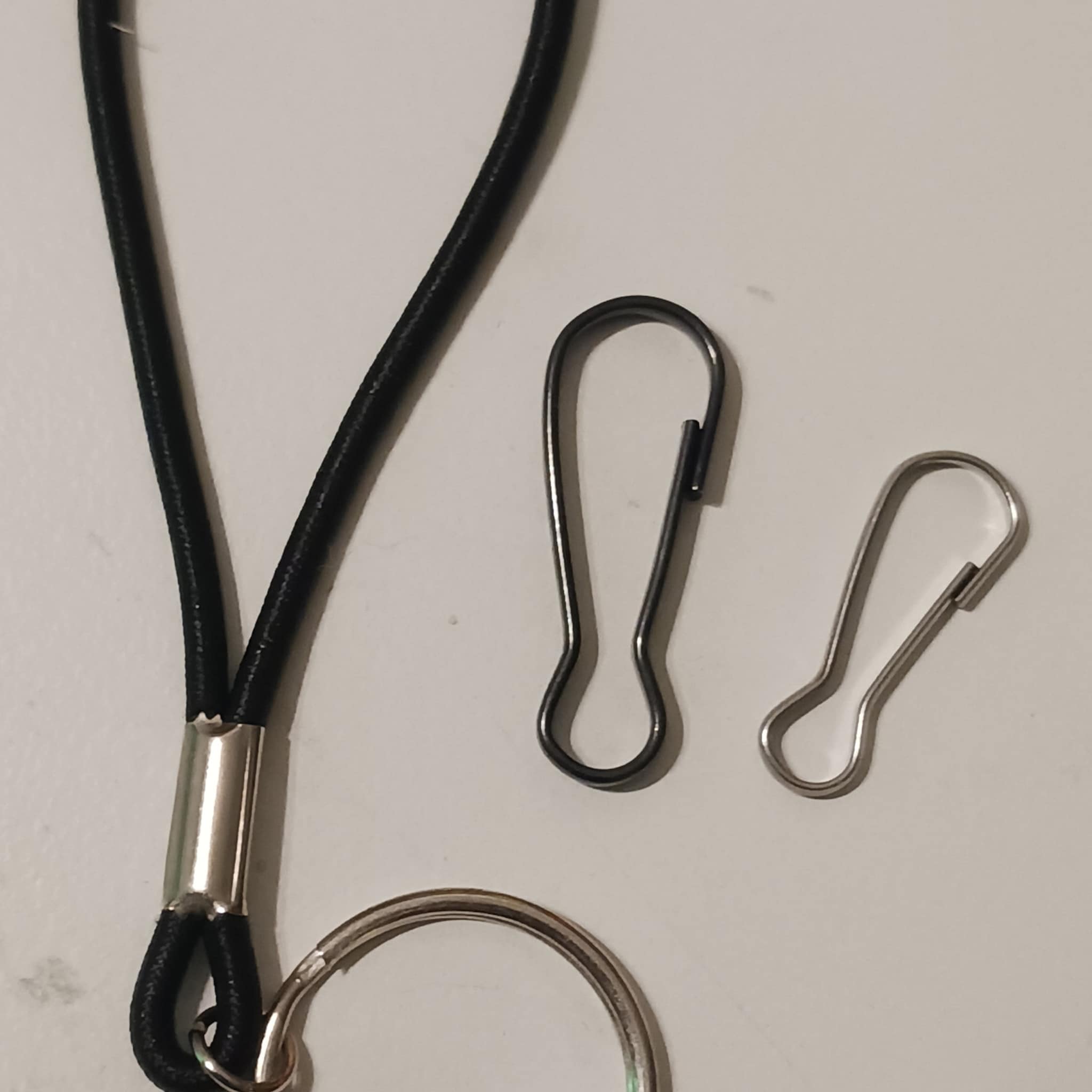 Lanyard with black cord and metal clasp, silver ring and hooks, on white background